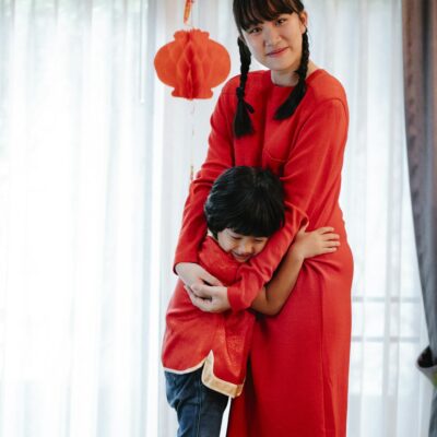 Mother and son celebrating Chinese New Year with traditional food and festive decorations indoors.