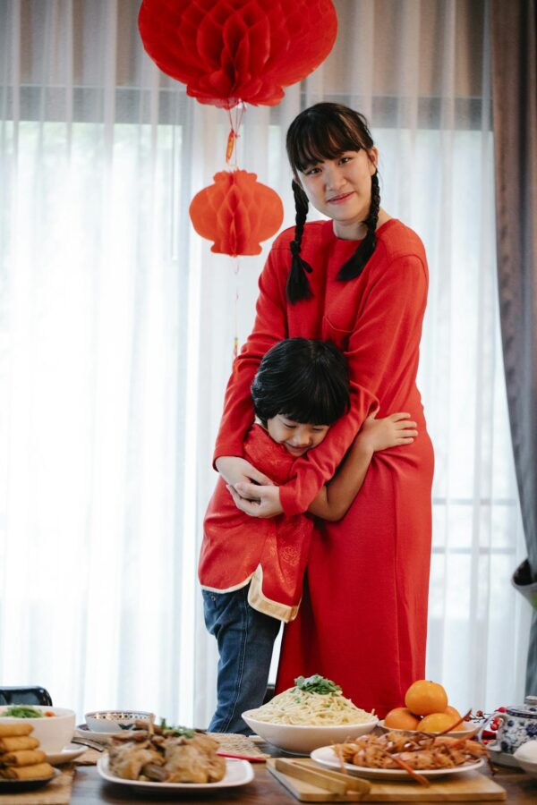 Mother and son celebrating Chinese New Year with traditional food and festive decorations indoors.